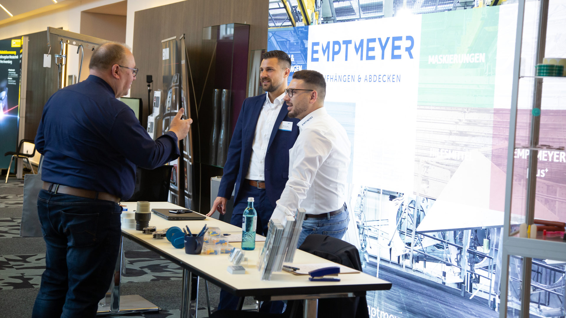 Drei Herren im Gespräch an einem Ausstellungsstand 