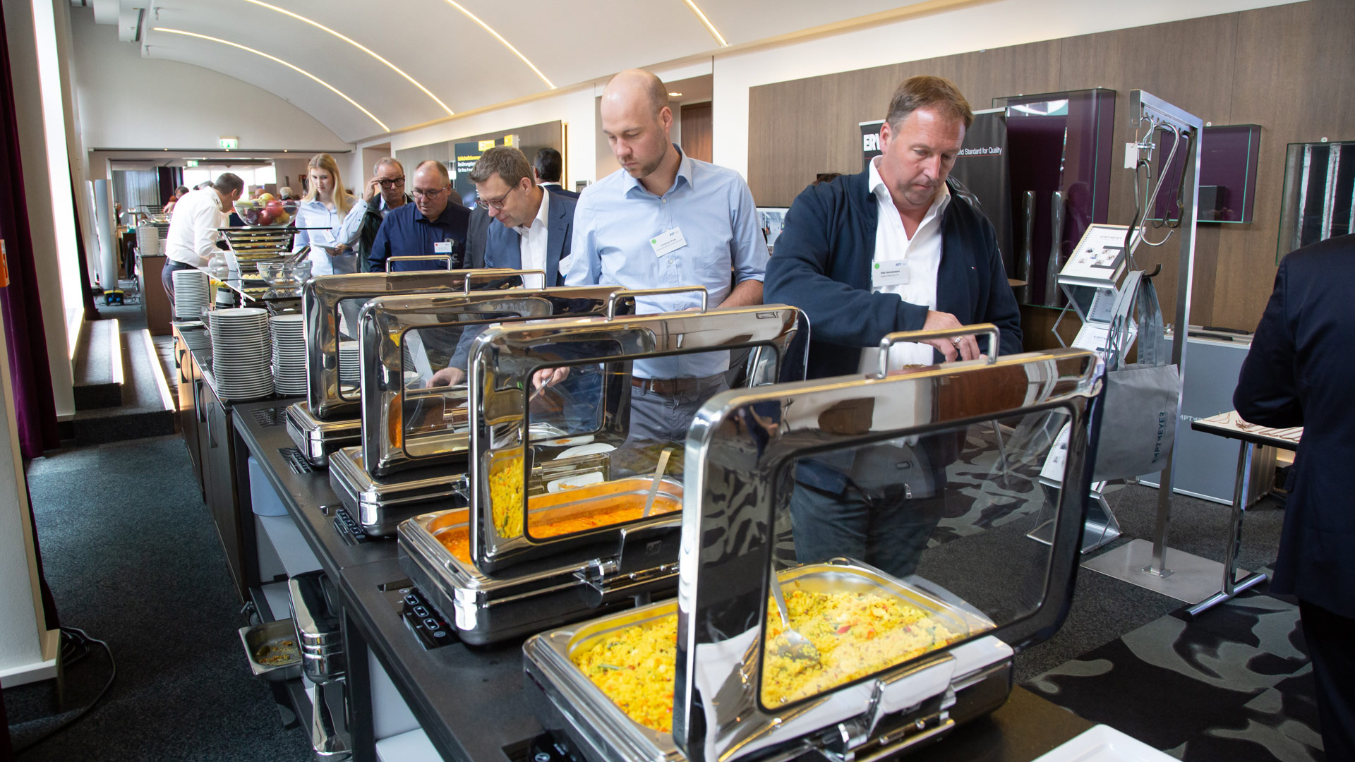 Konferenzteilnehmer an der Cateringstation während der Mittagspause