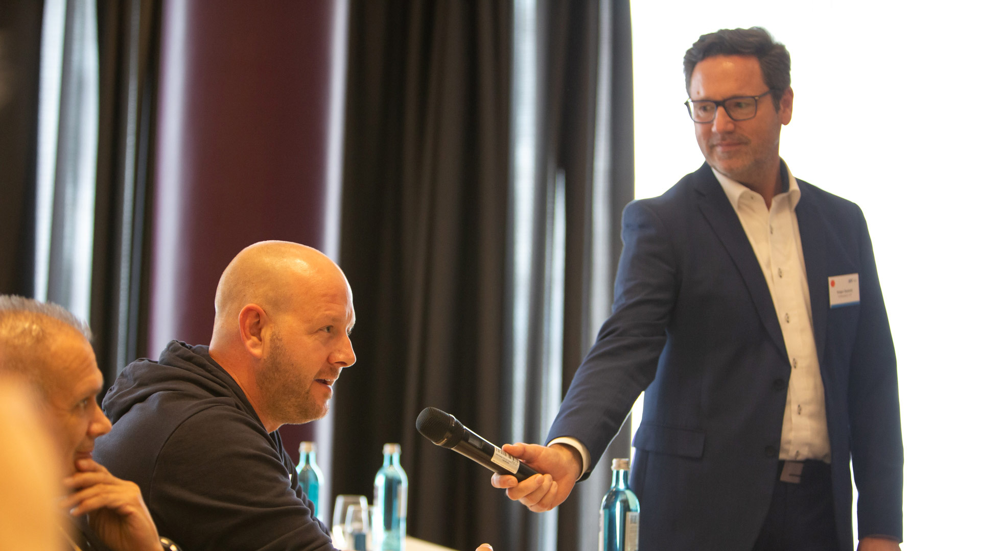 Frage aus dem Publikum - Tagungsleiter reicht das Mikrofon an